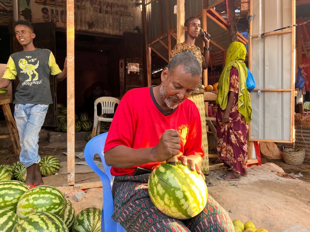 pexels-photo-13887954 A vendor skillfully slices watermelon at an outdoor market in Mogadishu, Somalia.