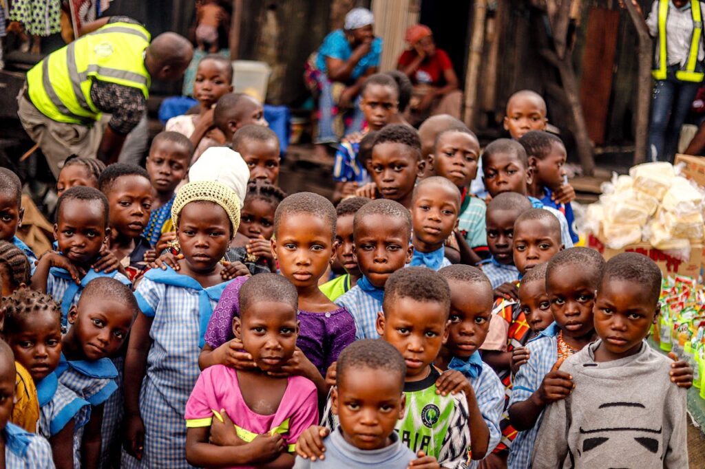 pexels-photo-9968380-2 A group of smiling African children posing outdoors in colorful attire. Vibrant community spirit.