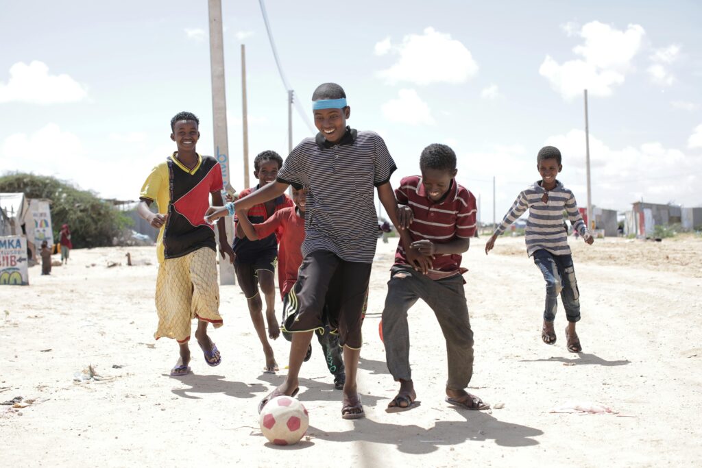 pexels-photo-5648177-5648177 A group of Somali children playing soccer on a sunny day, showcasing joy and friendship.